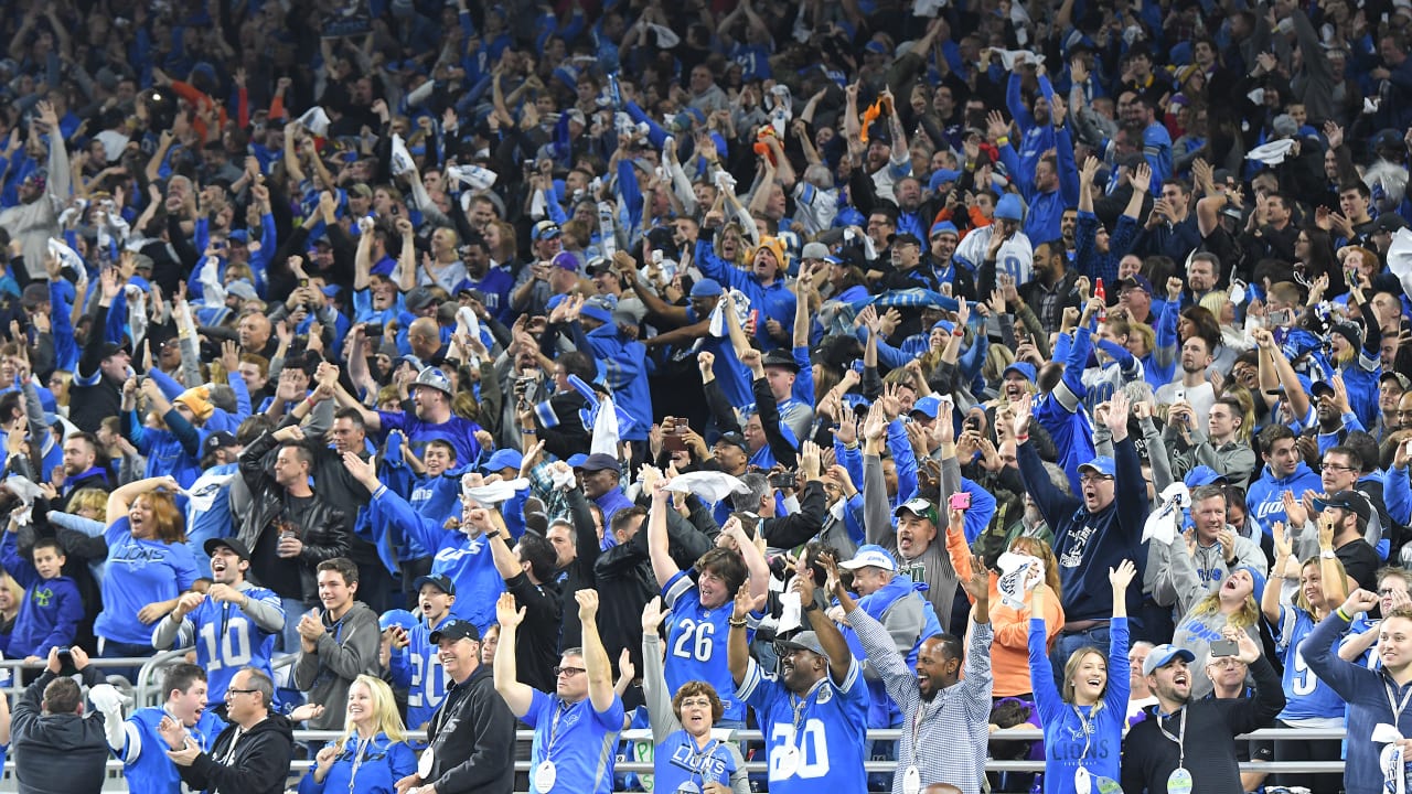 Excited Detroit Lions fans cheering together in a packed Ford Field crowd