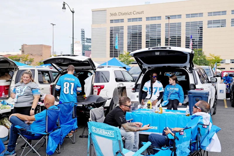 Detroit Lions fans tailgating with food, games, and team gear before kickoff